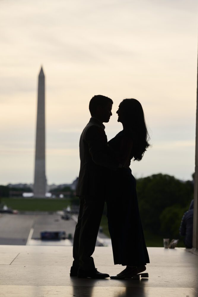 Silhouetted couple standing face to face with the Washington Monument blurred in the background